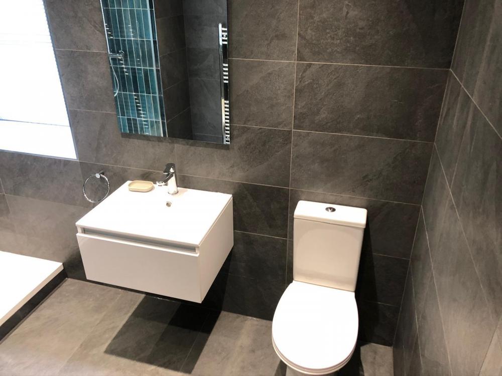 Wall-hung basin, mirror and toilet with charcoal bathroom tiles