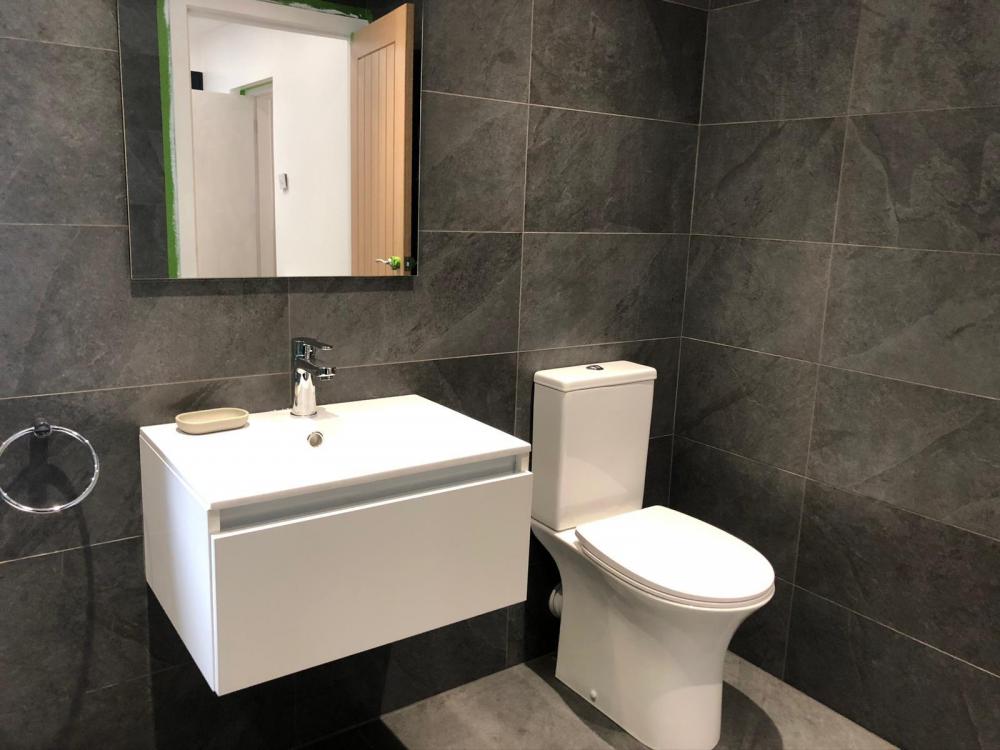 Charcoal tiled bathroom with white basin unit and close-coupled toilet