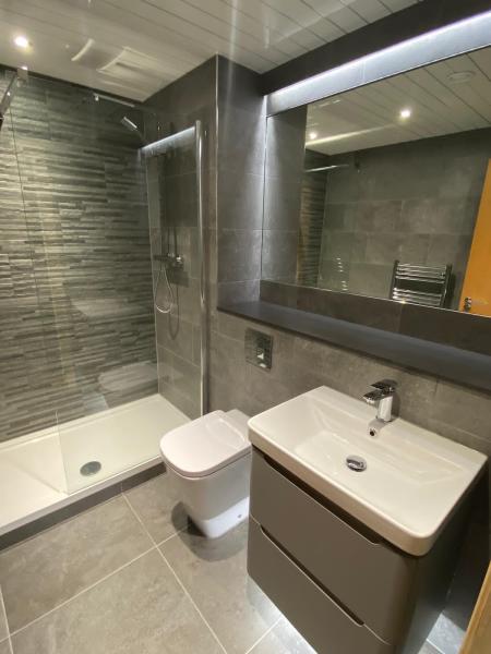 Walk-in shower with textured tiles, vanity and a wide mirror